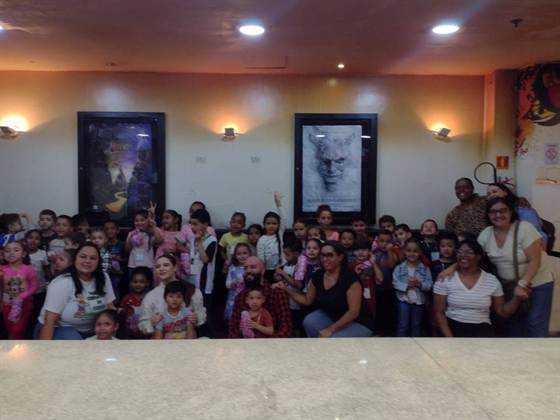 Outra foto da turma no saguão do cinema, com cartazes de filmes ao fundo