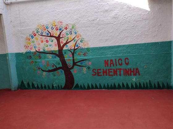 Mural da árvore de mãozinhas coloridas com o nome NAICC Sementinha